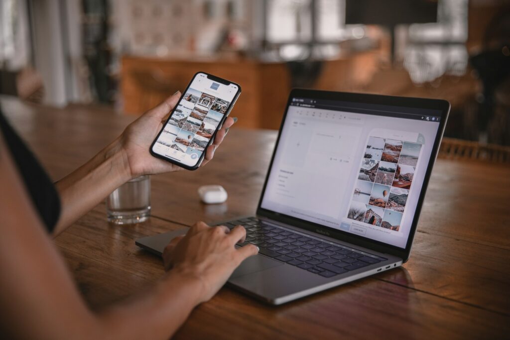 Website auf dem Laptop und auf dem Smartphone in der Hand an einem Holztisch